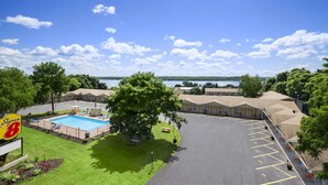 A motel with a swimming pool, a parking lot, and a view of a lake. - Super 8 by Wyndham Brockville (Elizabethtown-Kitley)