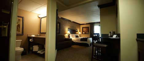 Una habitación de hotel con baño, cama, escritorio y silla.