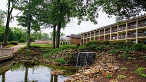 A hotel with a landscaped garden, a pond, and a waterfall. - Fourwinds Lakeside Inn & Marina (Bloomington)