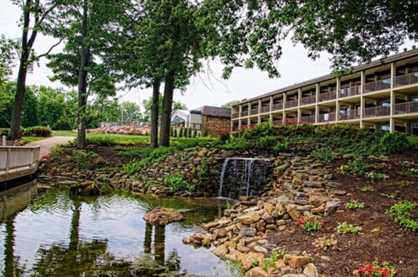 A hotel with a landscaped garden, a pond, and a waterfall.