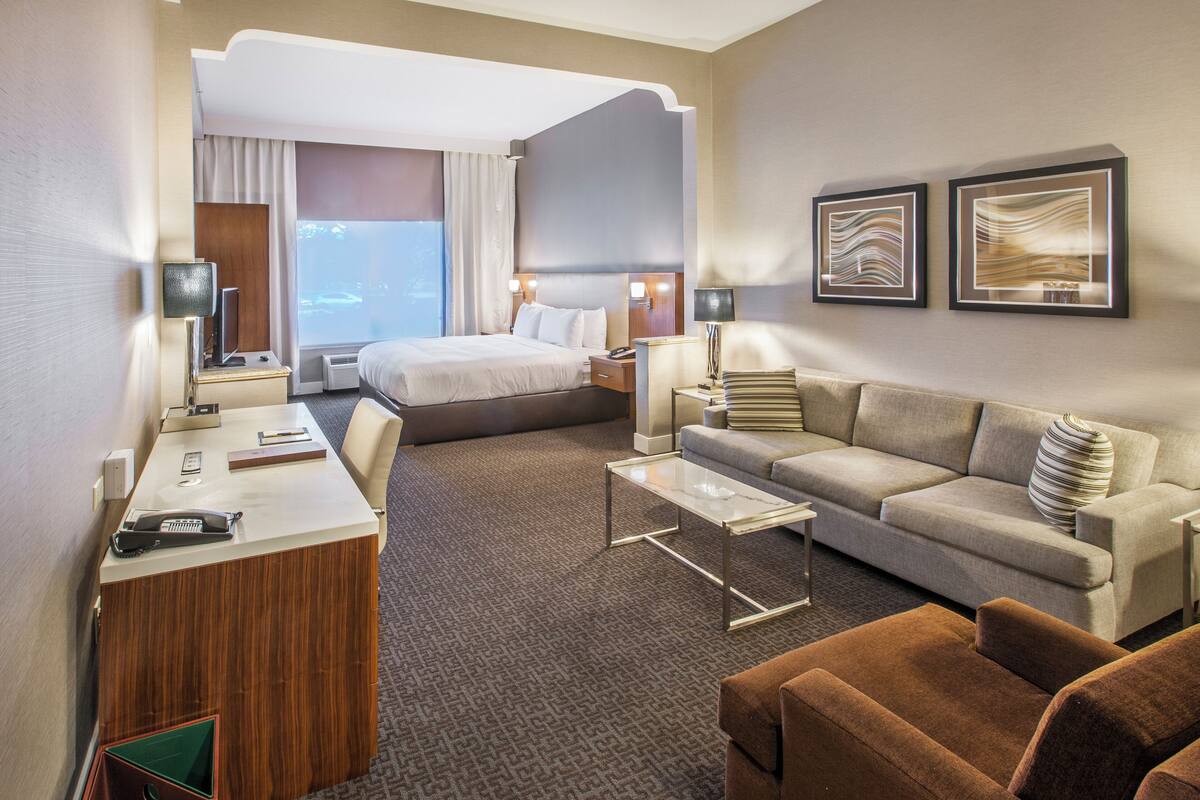 A hotel room with a bed, a sofa, a desk, and a coffee table.