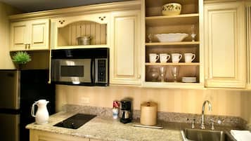 A kitchen with a built-in microwave, a stainless steel refrigerator, a granite countertop, and a sink with a faucet.