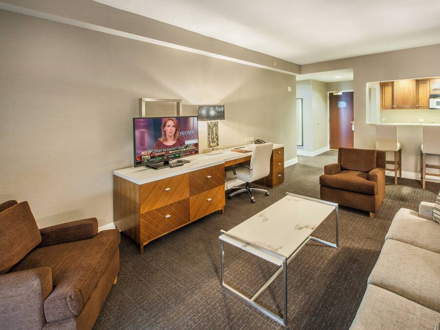 A modern living room with a TV, a wooden cabinet, a desk, a chair, and a sofa.