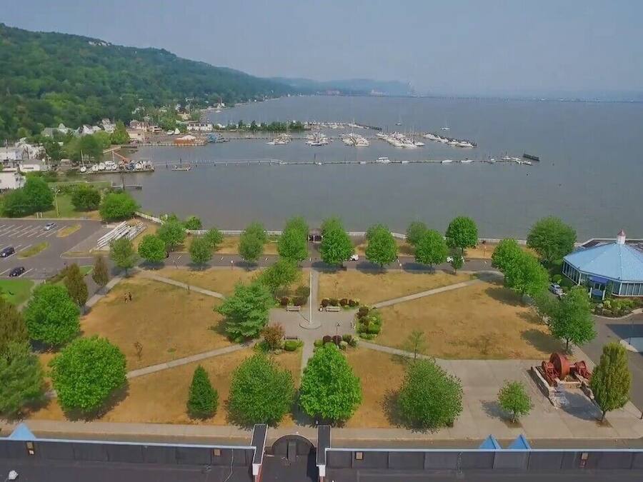 A waterfront view with a parking lot, trees, and a building with a blue roof.