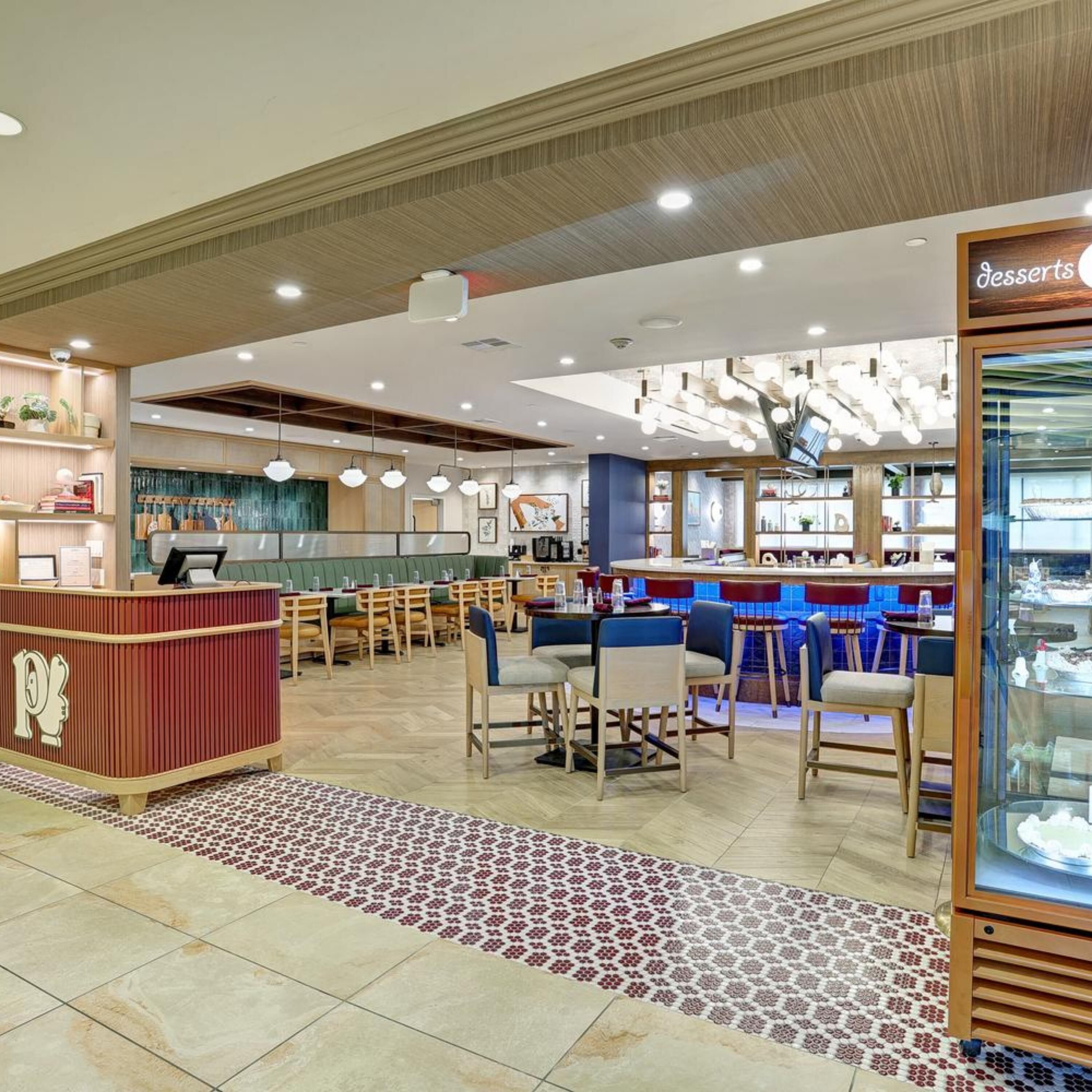 Un intérieur de restaurant moderne avec un bar, des tables et un présentoir à desserts.