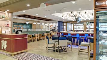 Un intérieur de restaurant moderne avec un bar, des tables et un présentoir à desserts.