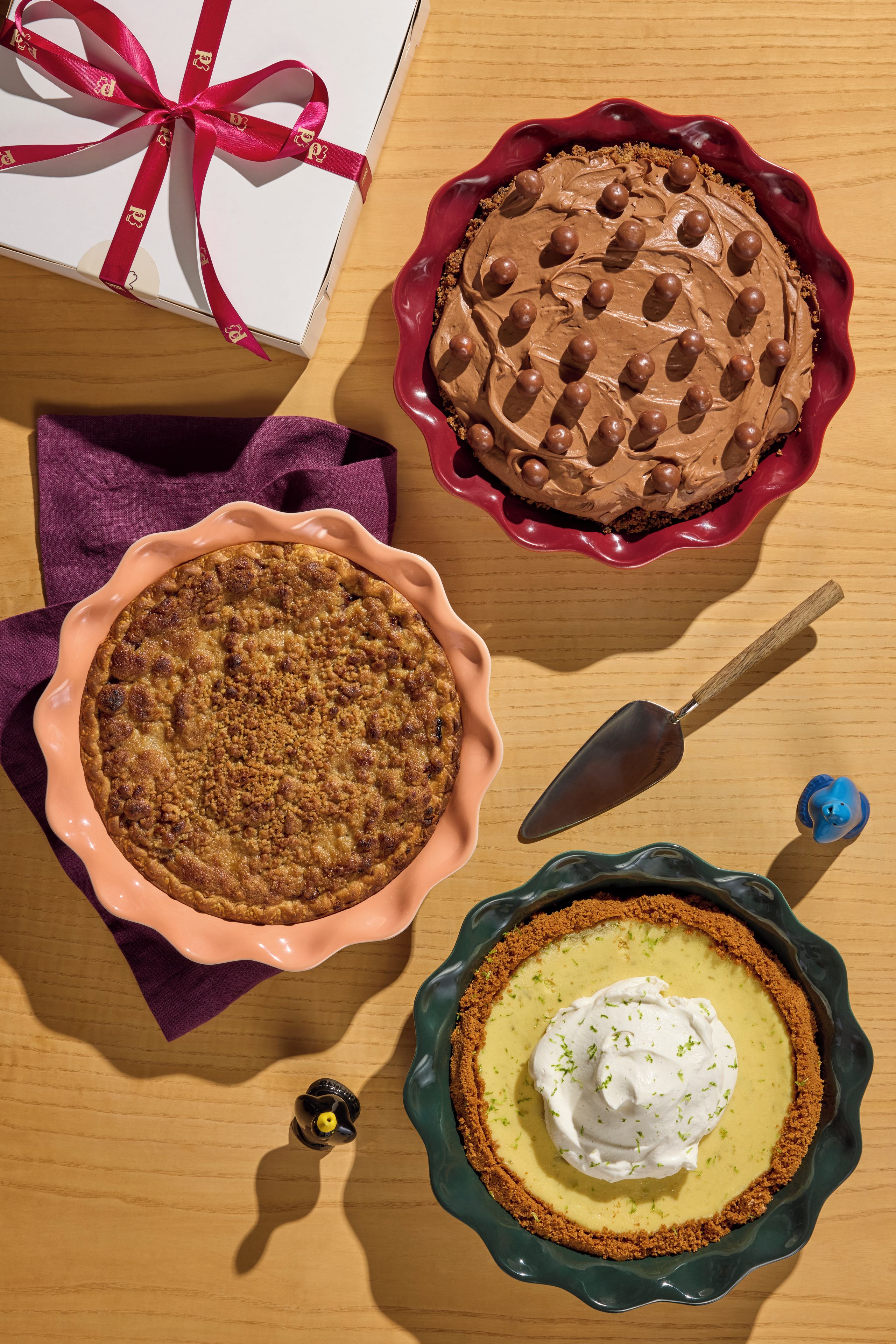 Three pies in different dishes on a wooden table.