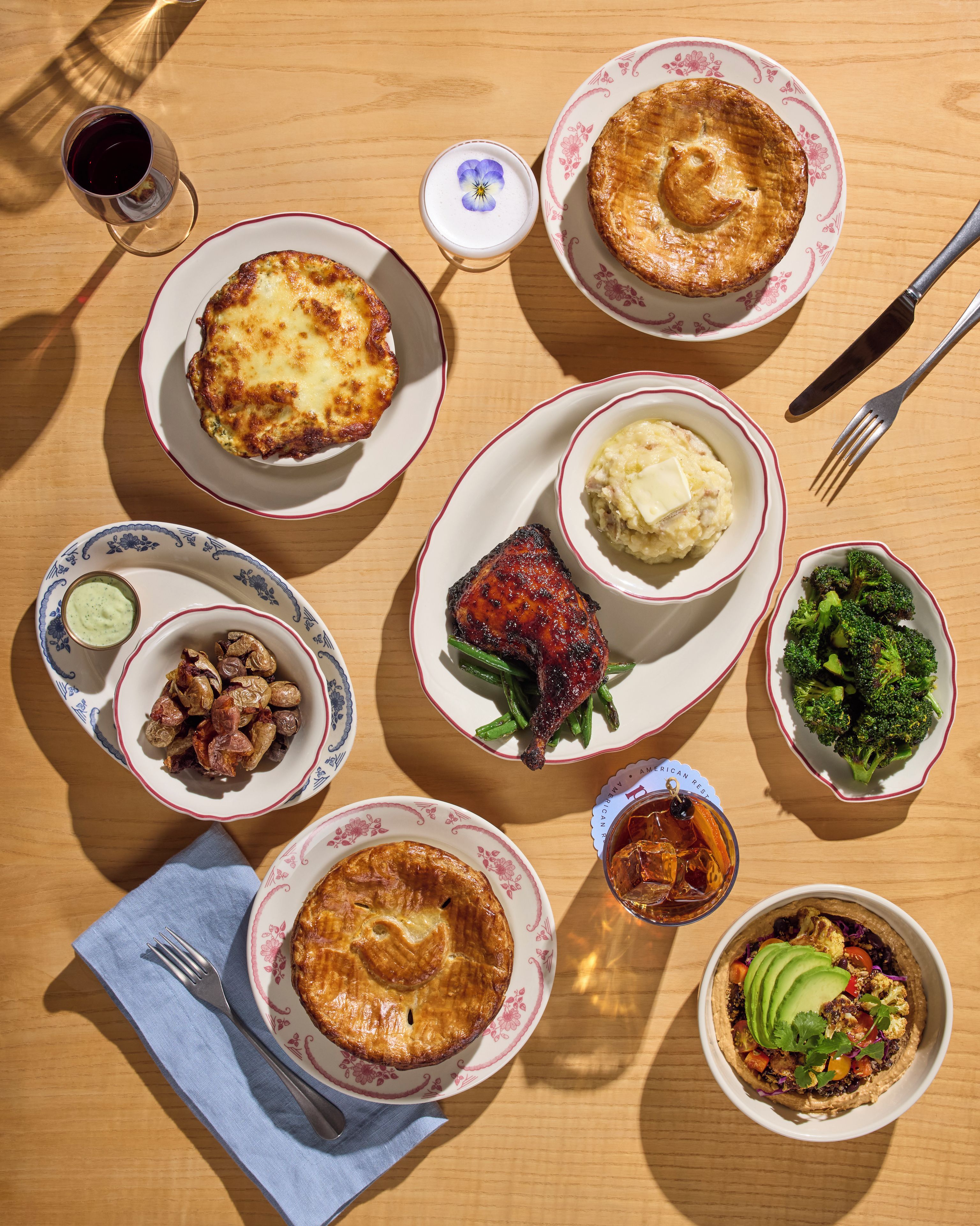A table set with various dishes including a pie, mashed potatoes, roasted chicken, and vegetables.