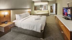 A hotel room with a large bed, a bedside table with a lamp, a TV, and a bathroom with a mirror and sink. - DoubleTree by Hilton Hotel Nanuet (Nanuet)