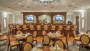 A hotel dining area with multiple tables and chairs, a bar with a counter and bar stools, and two televisions mounted on the wall. - DoubleTree by Hilton Hotel Nanuet (Nanuet)