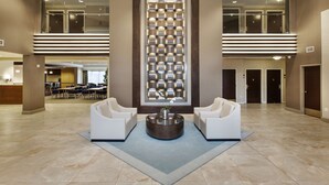 A spacious lobby with a central seating area, a decorative wall, and a reception desk in the background. - DoubleTree by Hilton Hotel Nanuet (Nanuet)