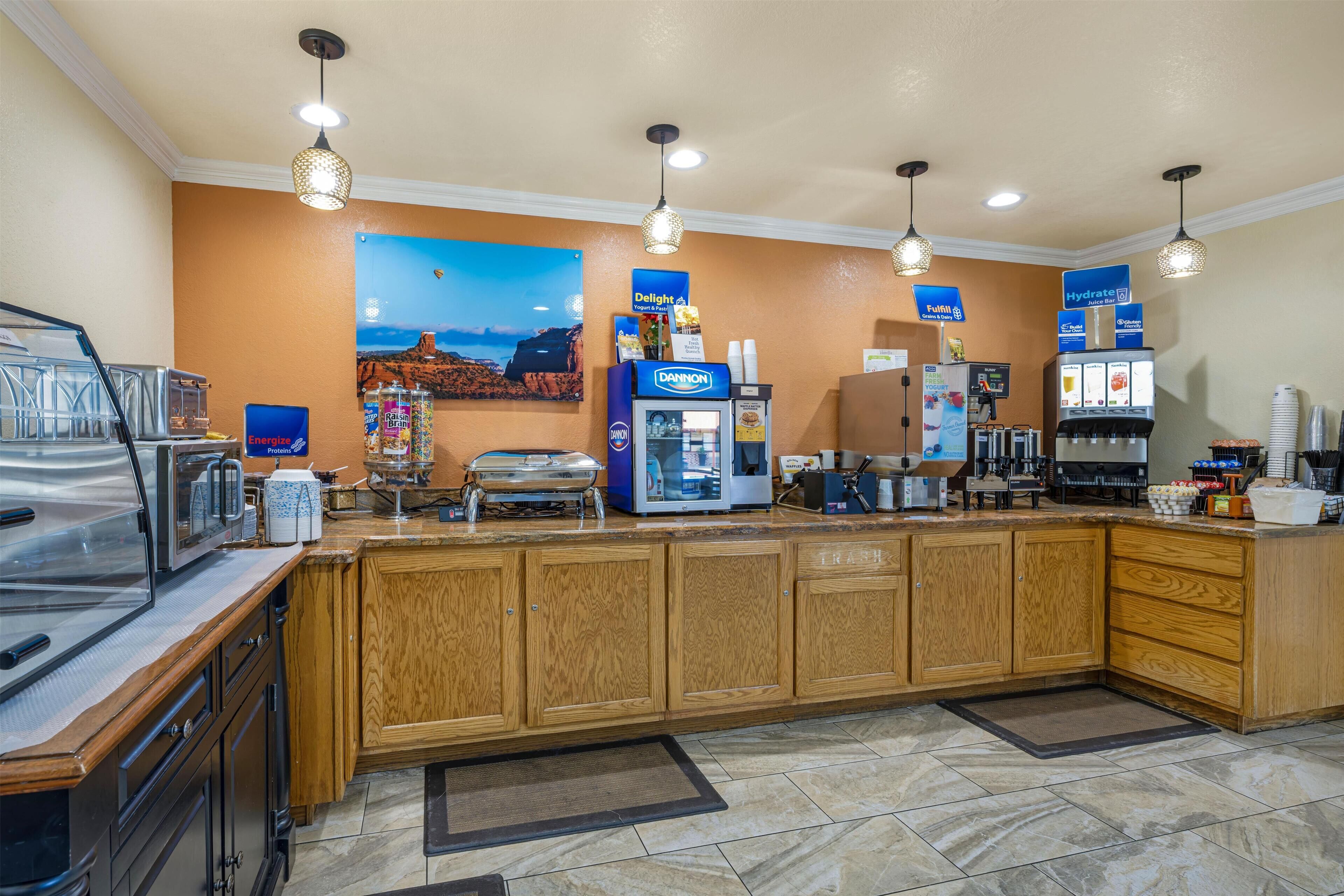 A hotel kitchen with a coffee station, a Dannon yogurt cooler, and a refrigerator.