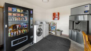 A compact laundry area with a washing machine, a refrigerator, and a vending machine.