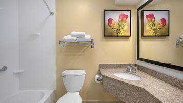 Ein Badezimmer mit Toilette, Waschbecken mit Granitplatte und Duschbereich.