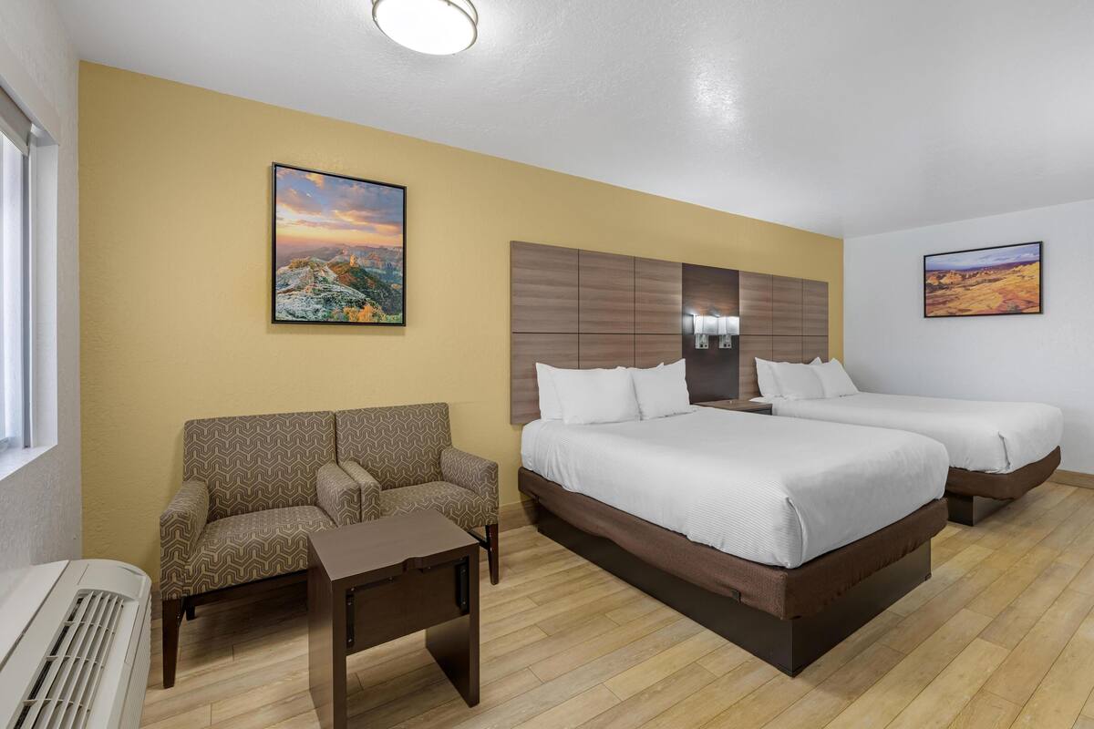 Ein Hotelzimmer mit einem Bett, zwei Nachttischen, einem Sofa und einem an der Wand befestigten Fernseher.