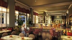 A restaurant with multiple seating areas, including booths and tables, and a bar in the background. - The Stoneleigh, Autograph Collection (Dallas)
