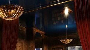 A dimly lit room with a chandelier, red curtains, a bookshelf, and a seating area with round tables and cushions. - The Stoneleigh, Autograph Collection (Dallas)