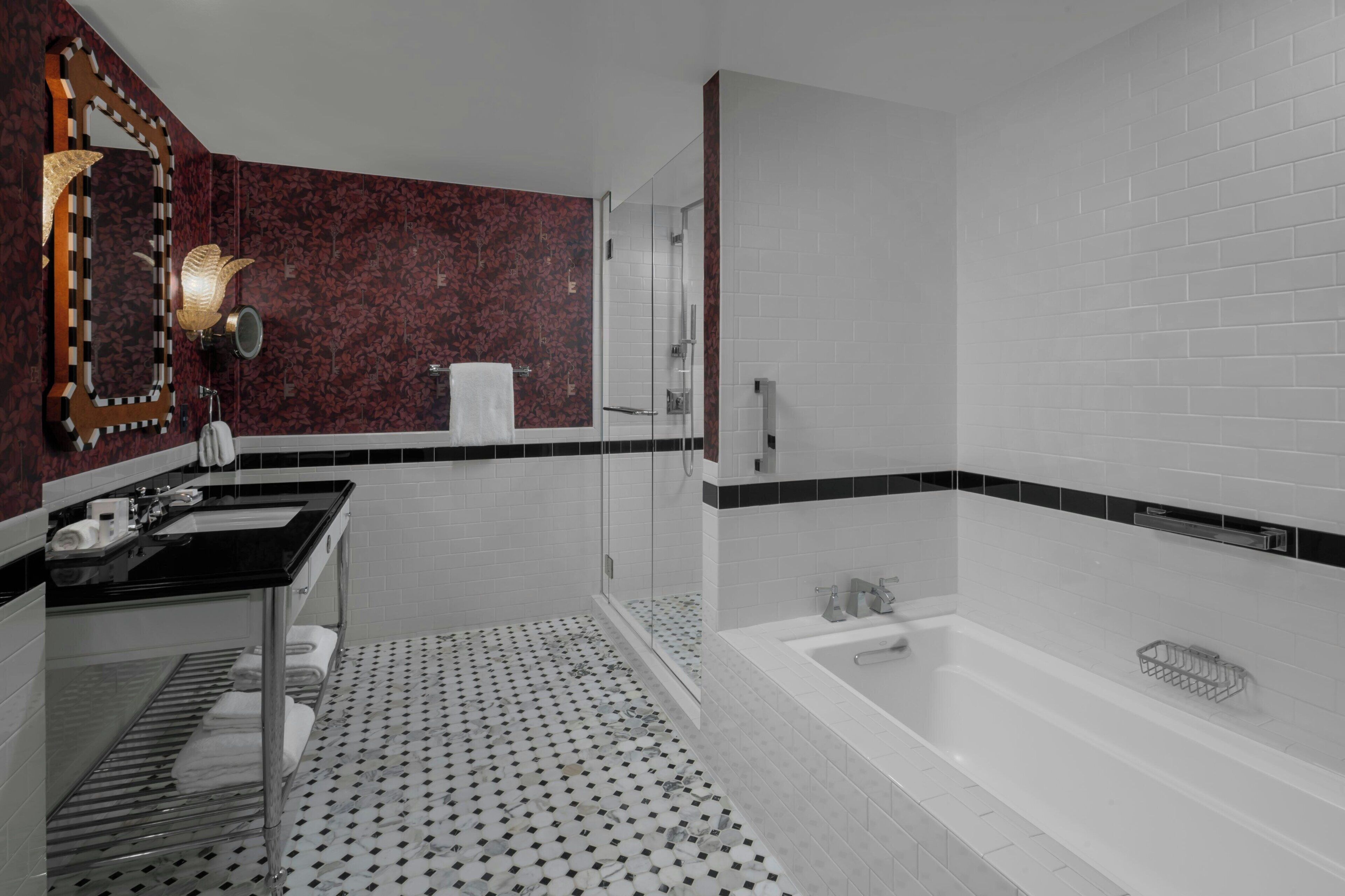 Un baño moderno con lavamanos de encimera negro, cabina de ducha de cristal y bañera blanca.
