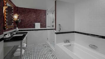 Un baño moderno con lavamanos de encimera negro, cabina de ducha de cristal y bañera blanca.