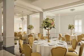 A formal dining room with round tables, gold chairs, and floral centerpieces. - The Stoneleigh, Autograph Collection (Dallas)