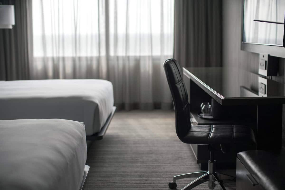 Une chambre d’hôtel avec deux lits, un bureau, une chaise et un téléviseur.