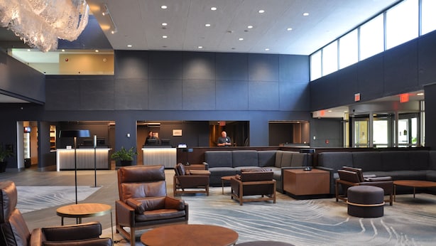 A spacious lobby with leather seating, a reception desk, and a modern chandelier. - Marriott Chicago Schaumburg (Schaumburg)