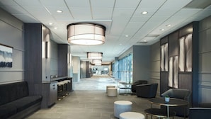 A modern hotel lobby with a long reception desk, seating areas, and large windows. - Marriott Chicago Schaumburg (Schaumburg)