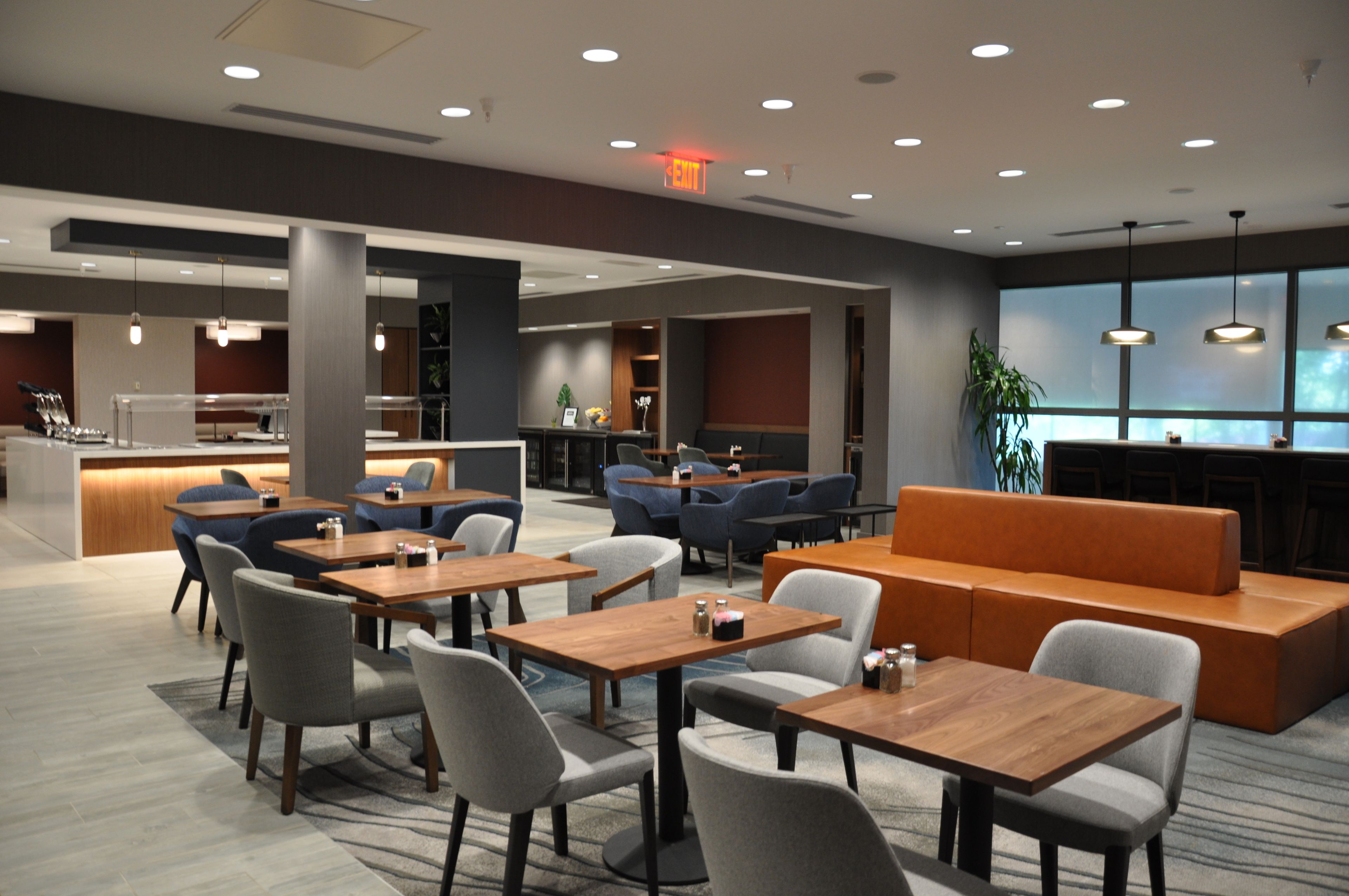 A modern hotel lobby with seating areas, tables, and a reception desk.