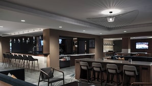 A modern bar area with a bar counter, seating, and a television screen. - Marriott Chicago Schaumburg (Schaumburg)