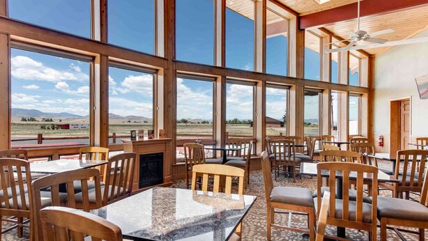 A restaurant with large windows, wooden chairs, and tables. - Best Western Movie Manor (Monte Vista)
