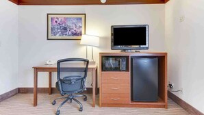 A hotel room with a wooden desk, a black office chair, a television, a microwave, and a refrigerator. - Best Western Movie Manor (Monte Vista)