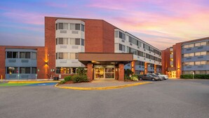 A multi-story hotel with a prominent entrance, parking area, and a clear sky. - Best Western Plus Ottawa City Centre (Ottawa)
