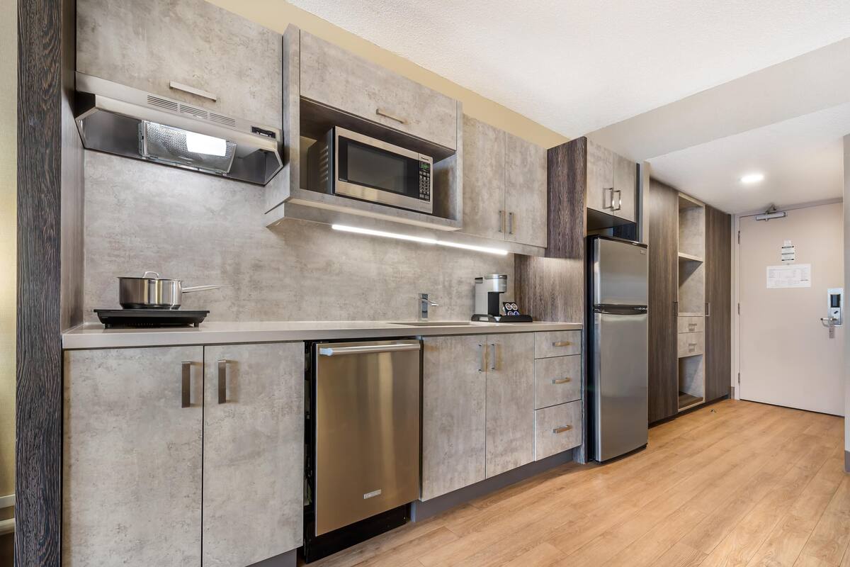 A modern kitchen with stainless steel appliances, a dishwasher, and wooden cabinets.