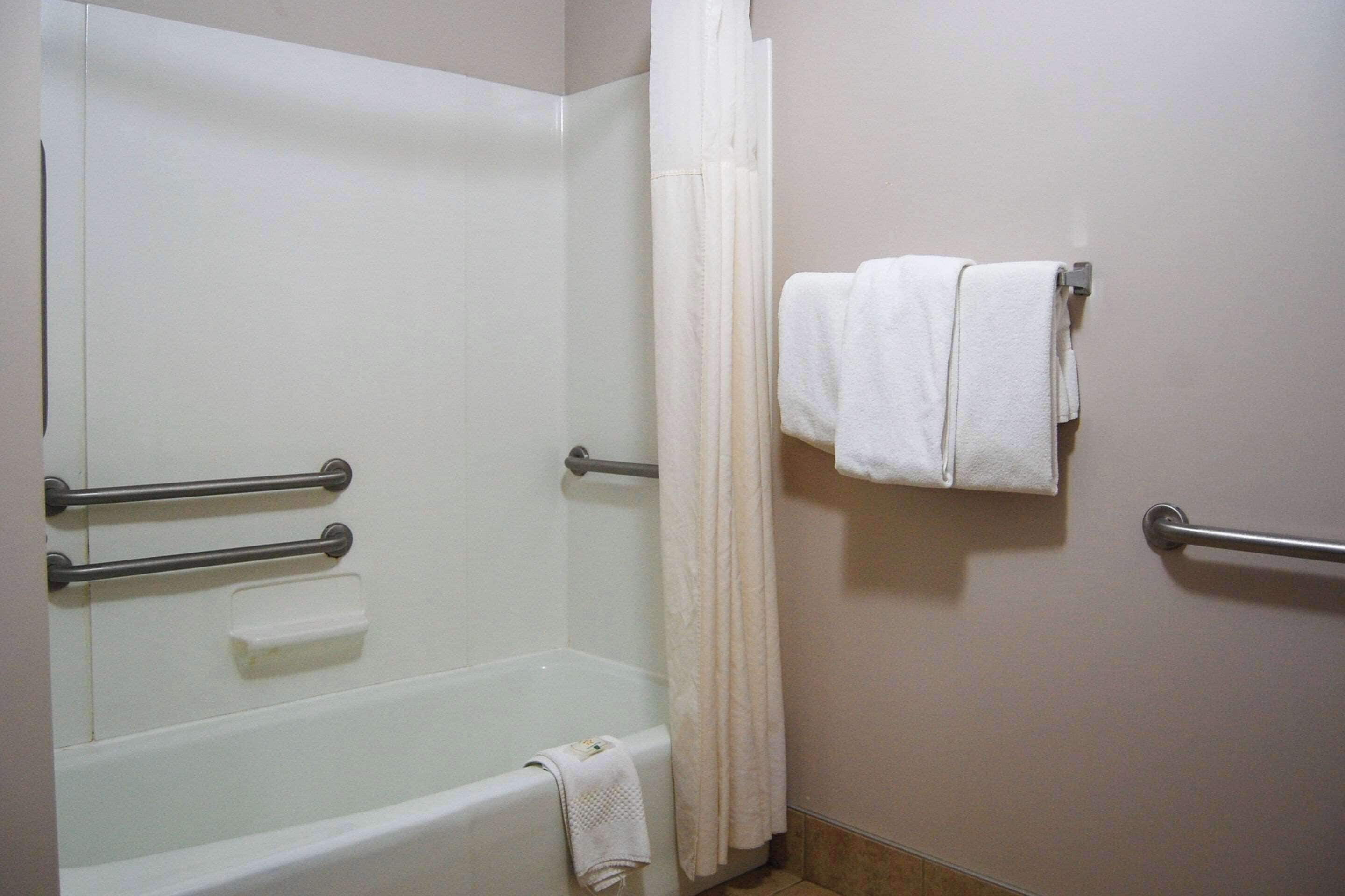 A bathroom with a bathtub, a shower curtain, and two towel racks with towels.