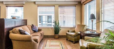 A living room with a sofa, armchairs, a coffee table, and a potted plant.