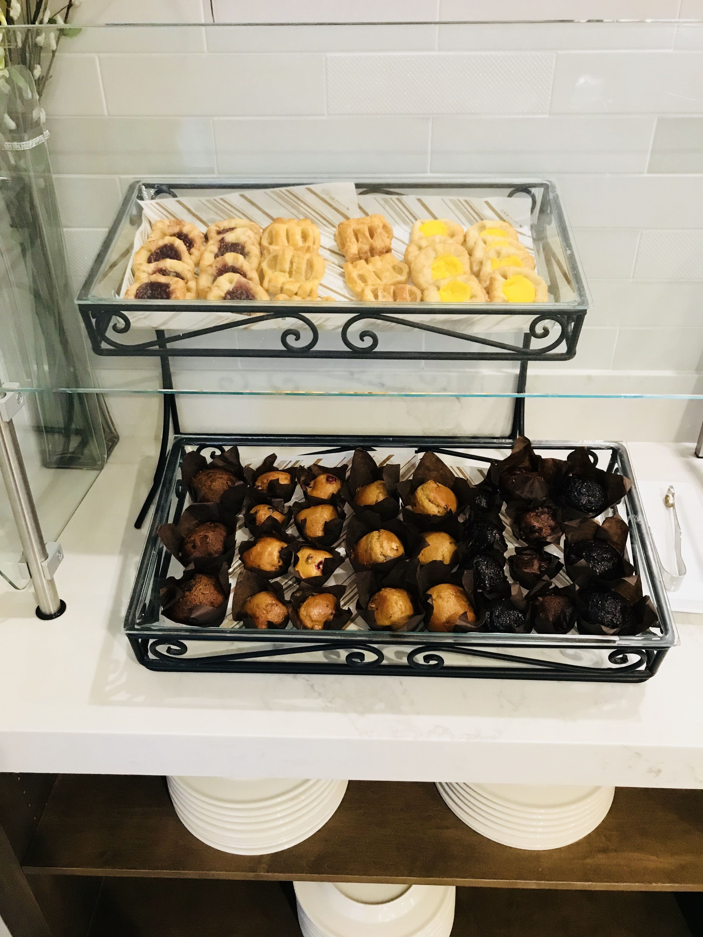 Un buffet proposant une variété de produits de boulangerie, notamment des pâtisseries et des muffins, présentés sur un présentoir en verre.