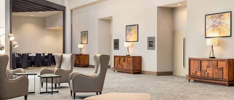 A hotel lobby with a gallery wall, seating areas, and a reception desk.