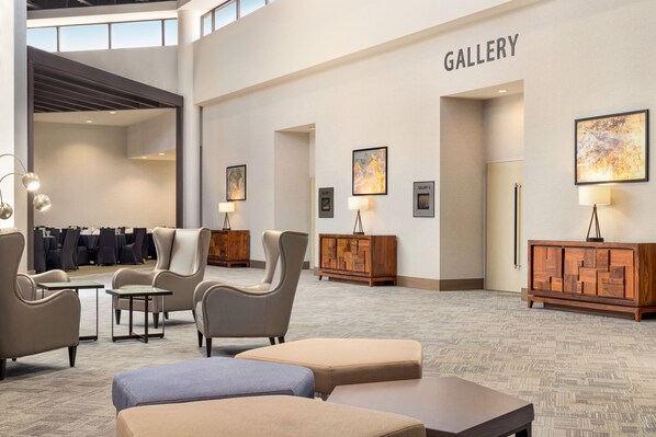 A hotel lobby with a gallery wall, seating areas, and a reception desk. - Holiday Inn Orlando International Airport by IHG (Orlando)