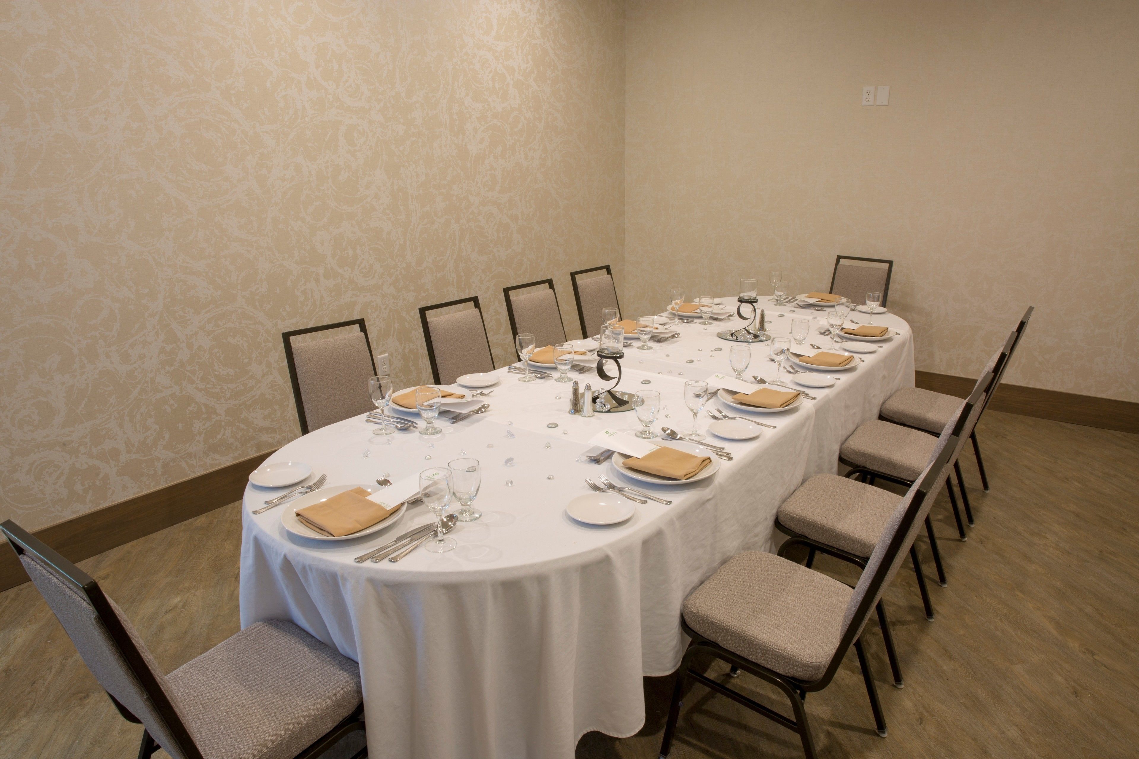 Une salle de conférence avec une longue table préparée pour une réunion, équipée de chaises et recouverte d’une nappe blanche.