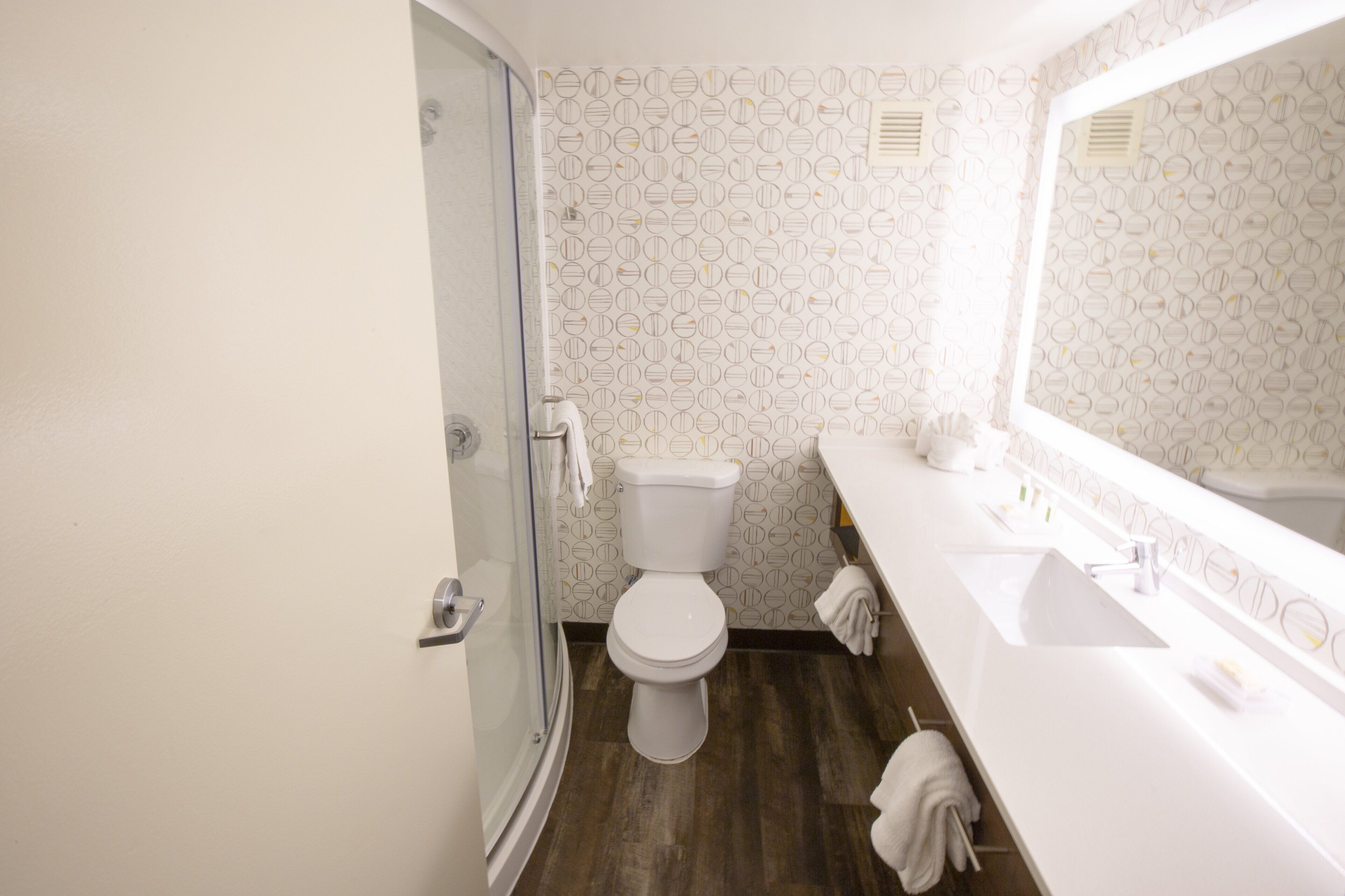 Et badeværelse med toilet, bruser og vask med spejl.