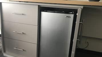 A compact kitchen with a built-in refrigerator, a microwave, and a flat-screen TV.