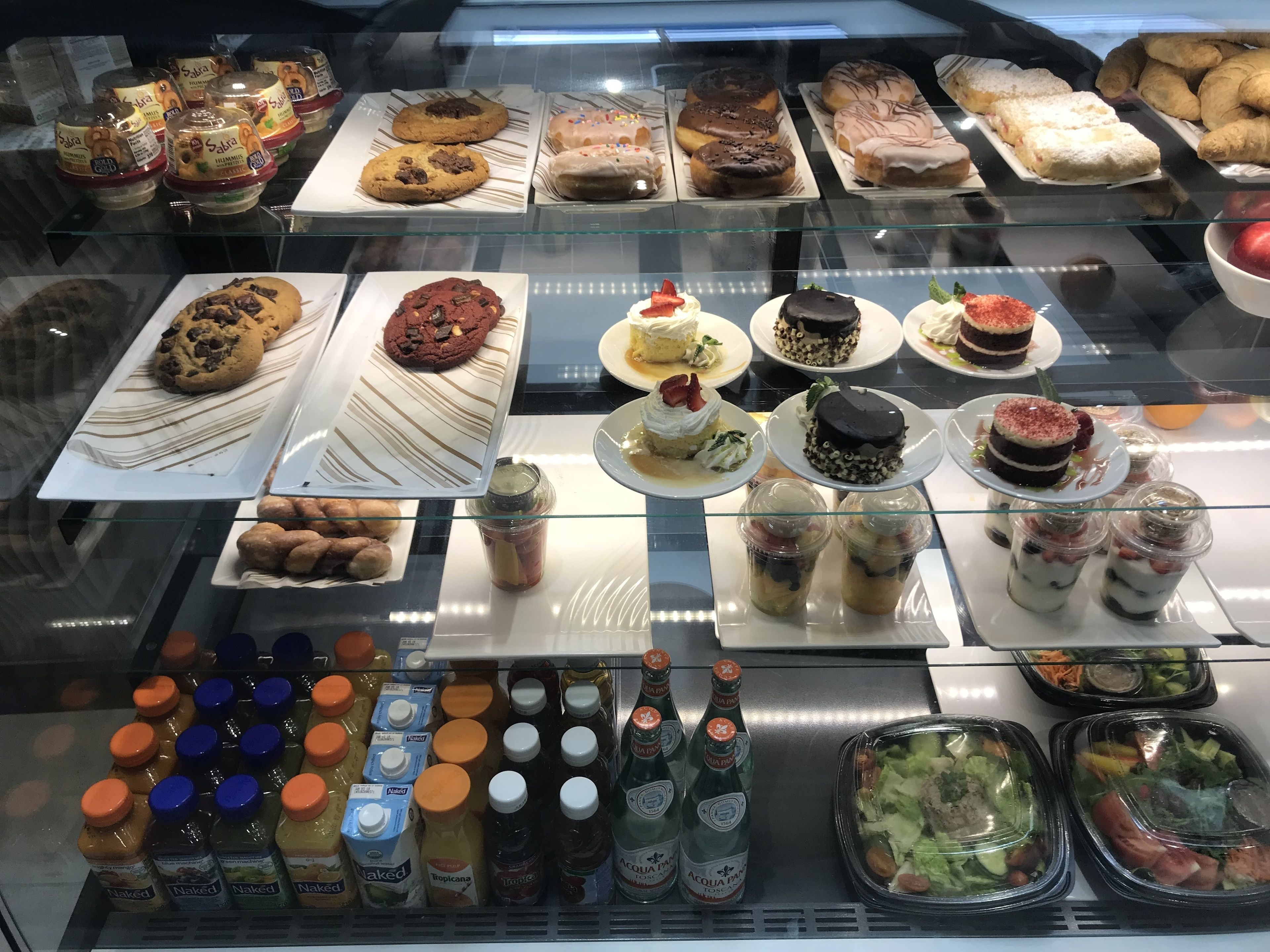 Vitrine com diversos produtos de pastelaria, sobremesas e bebidas.