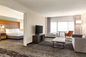 A hotel room with a bed, a TV, a desk, a chair, and a sofa. - Holiday Inn Orlando International Airport by IHG (Orlando)