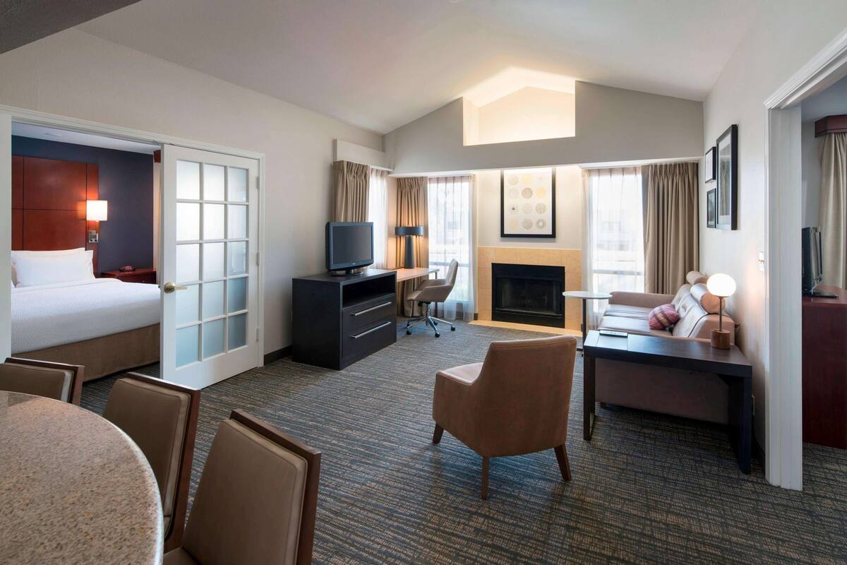 Habitación de hotel con cama, escritorio, televisión, chimenea y zona de estar.