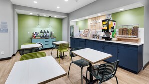Un café moderne avec des murs verts, des tables blanches et des chaises noires.