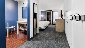 Une chambre d’hôtel avec un lit, un bureau, une chaise et un miroir.
