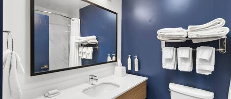 A modern bathroom with a white sink, a large mirror, and a blue accent wall.