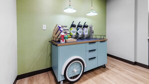 Un chariot muni de distributeurs de café et d’eau, une boîte de mouchoirs et un présentoir à mouchoirs.