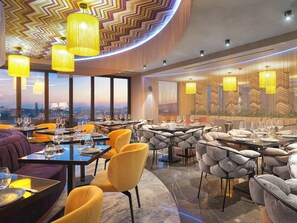 Un restaurant avec de nombreuses tables, des chaises et des lampes jaunes suspendues au plafond.