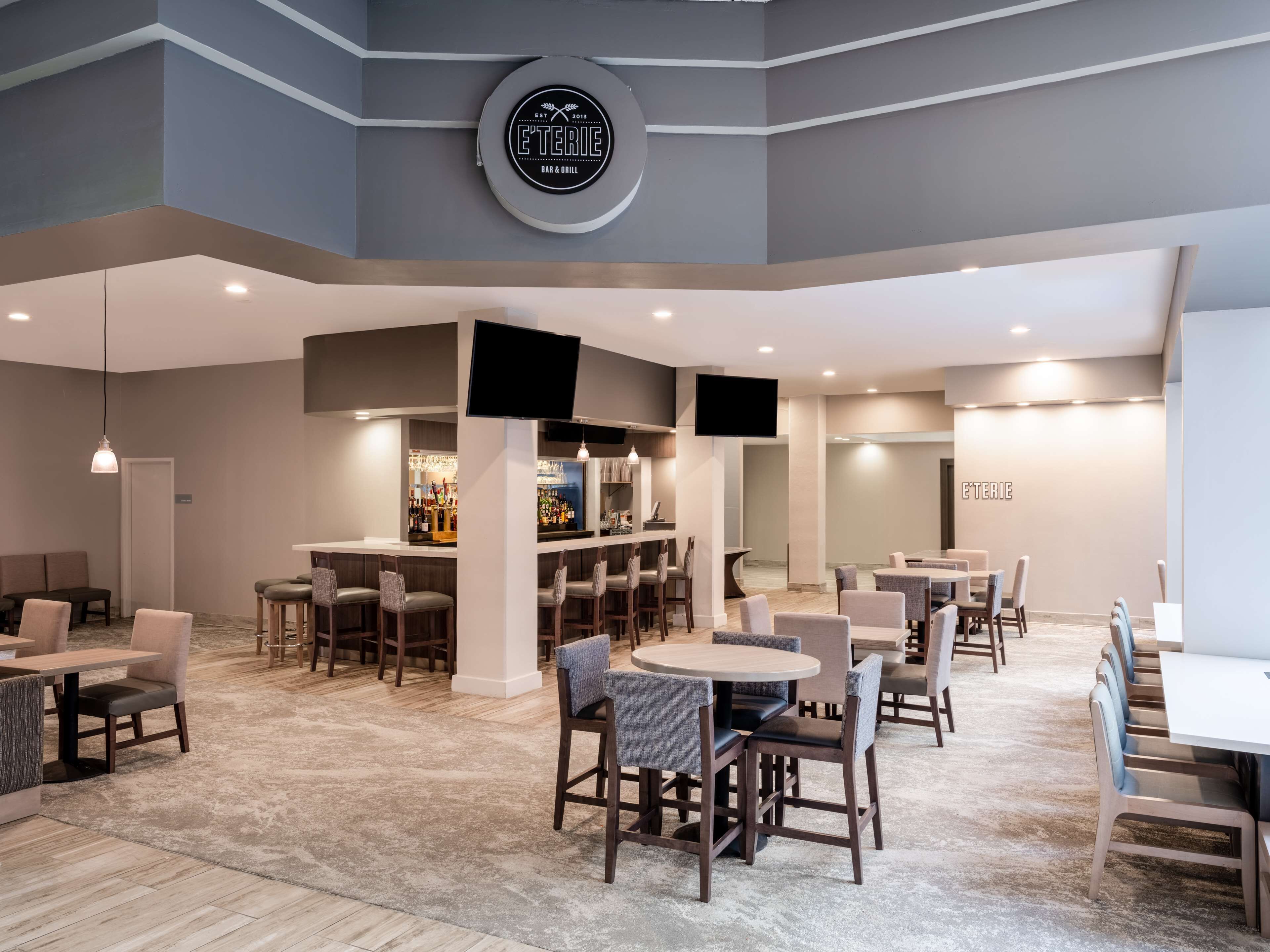 A modern bar and dining area with a bar counter, seating, and a mounted TV.